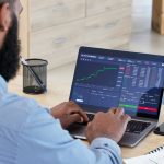 Laptop, finance and stock market with a man broker working in his office for trading investment or growth