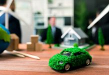 EV car model on table with blurred business people planning business marketing for eco-friendly car in background. Greener future with alternative energy charge utilization in business