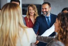 A diverse business team smiling and joining hands in a show of unity, care and teamwork.