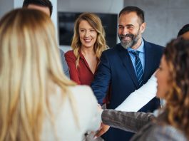 A diverse business team smiling and joining hands in a show of unity, care and teamwork.